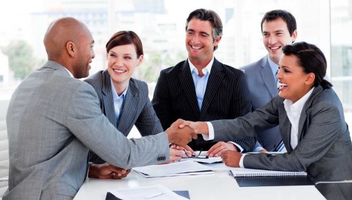 Group of business people happy and shaking hands, seated at a table because they have TuckNStay