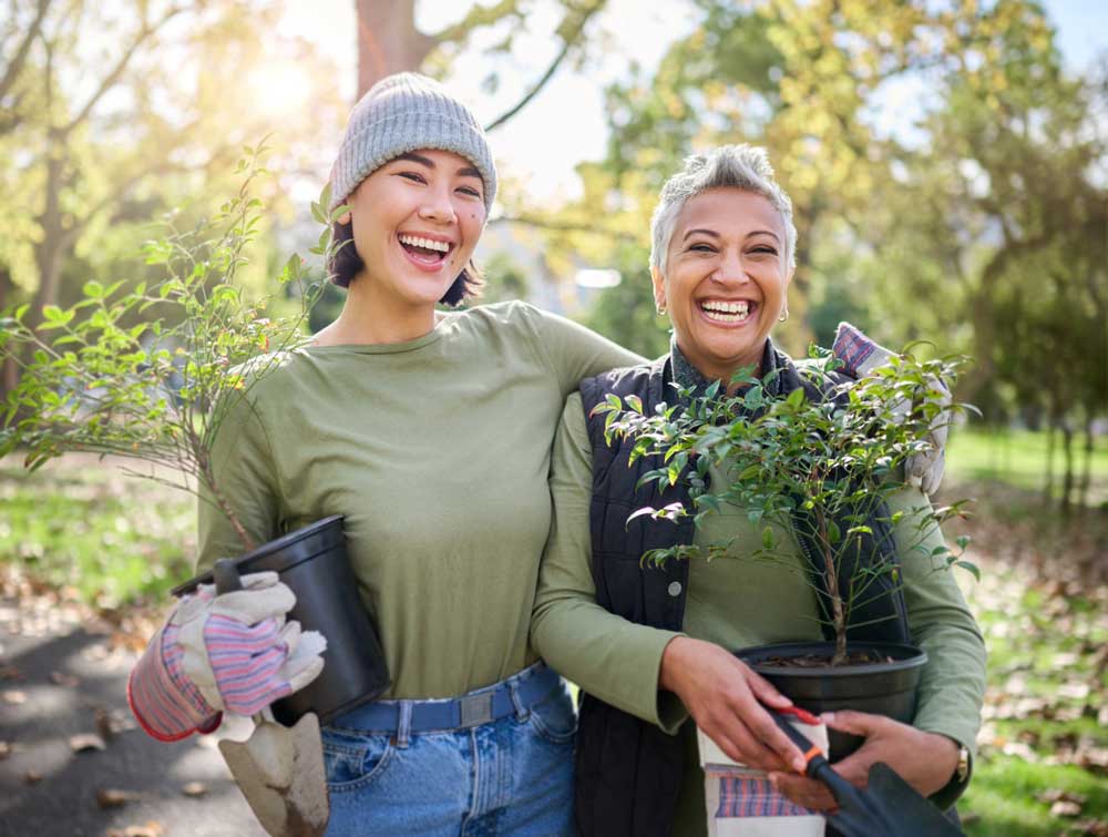 Two happy women outside holding plants